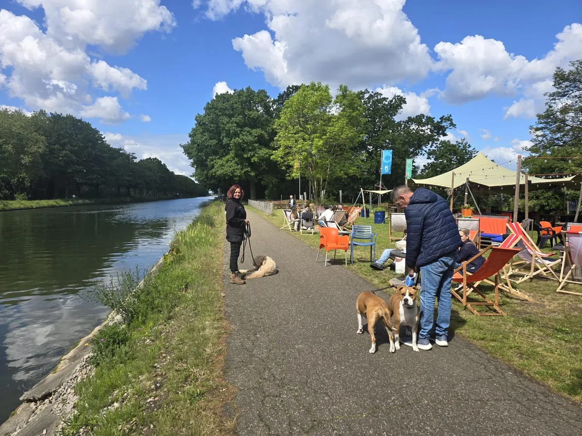 Hanneke en baasjes met hun honden op het pad langs het kanaal, naast een terras